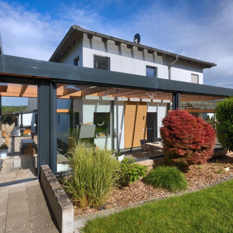 langlebige Terrassenüberdachung aus Holz/Alu mit geöffneten und geschlossenen Glasschiebetüren im Landkreis Lichtenfels